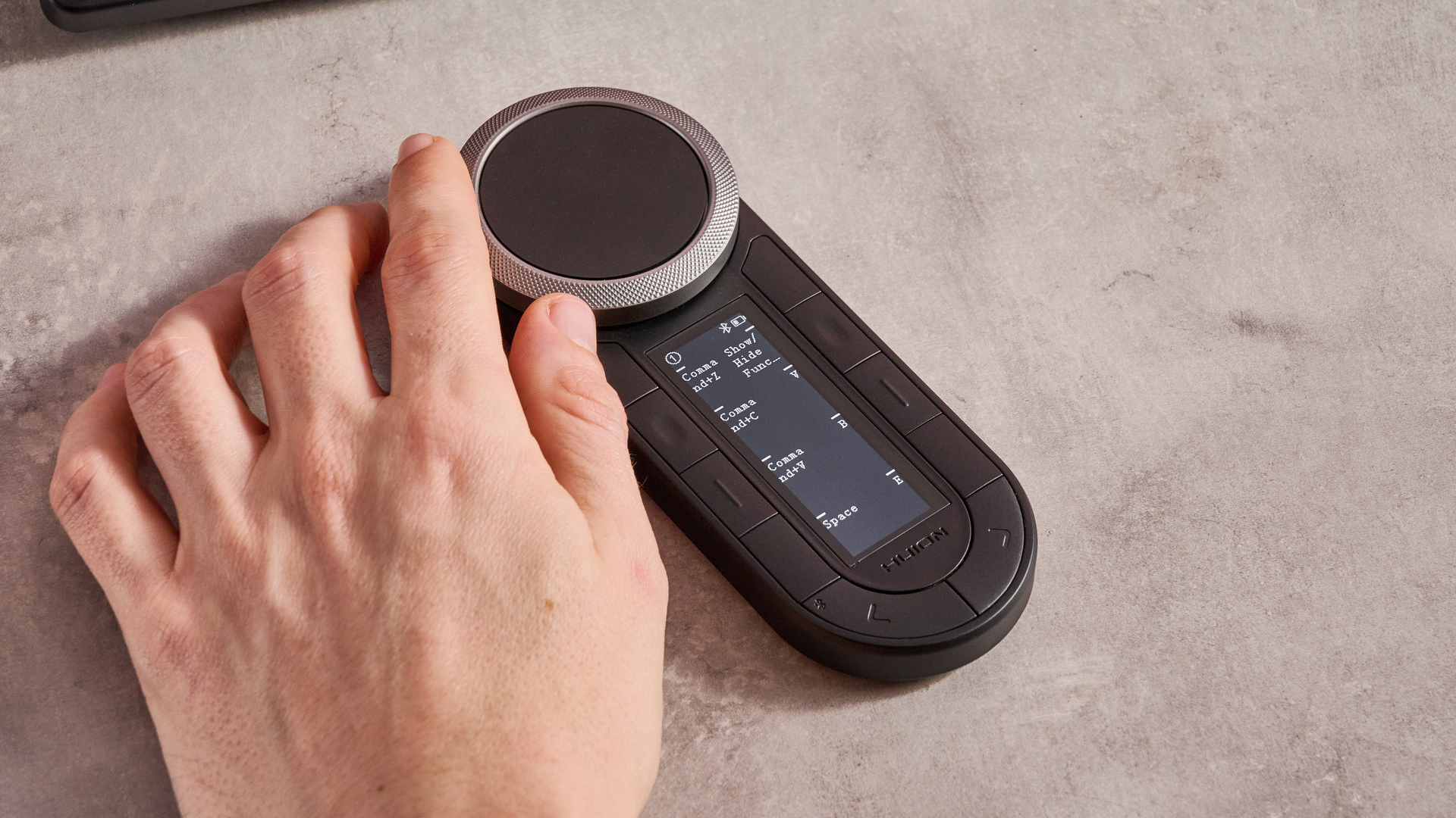 A hand adjusting one of the twin dials of the Huion Kamvas Pro 24 Gen 3's Keydial Remote.