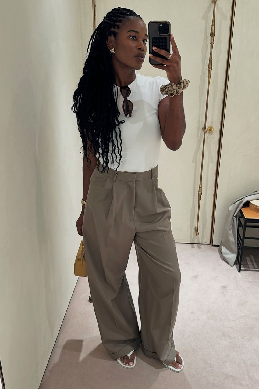 a woman wearing a white tee, tan pants, and white flip flops