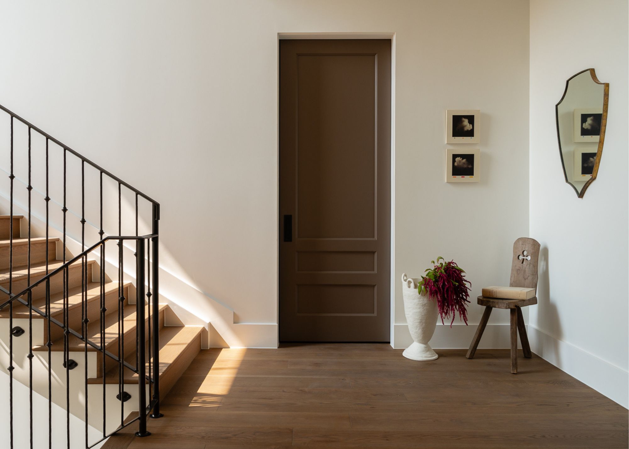 modern entryway with white walls, wooden floors, a chair in the corner with a wall mirror