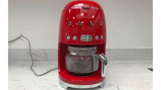 The red smeg drip coffee maker on a marble countertop