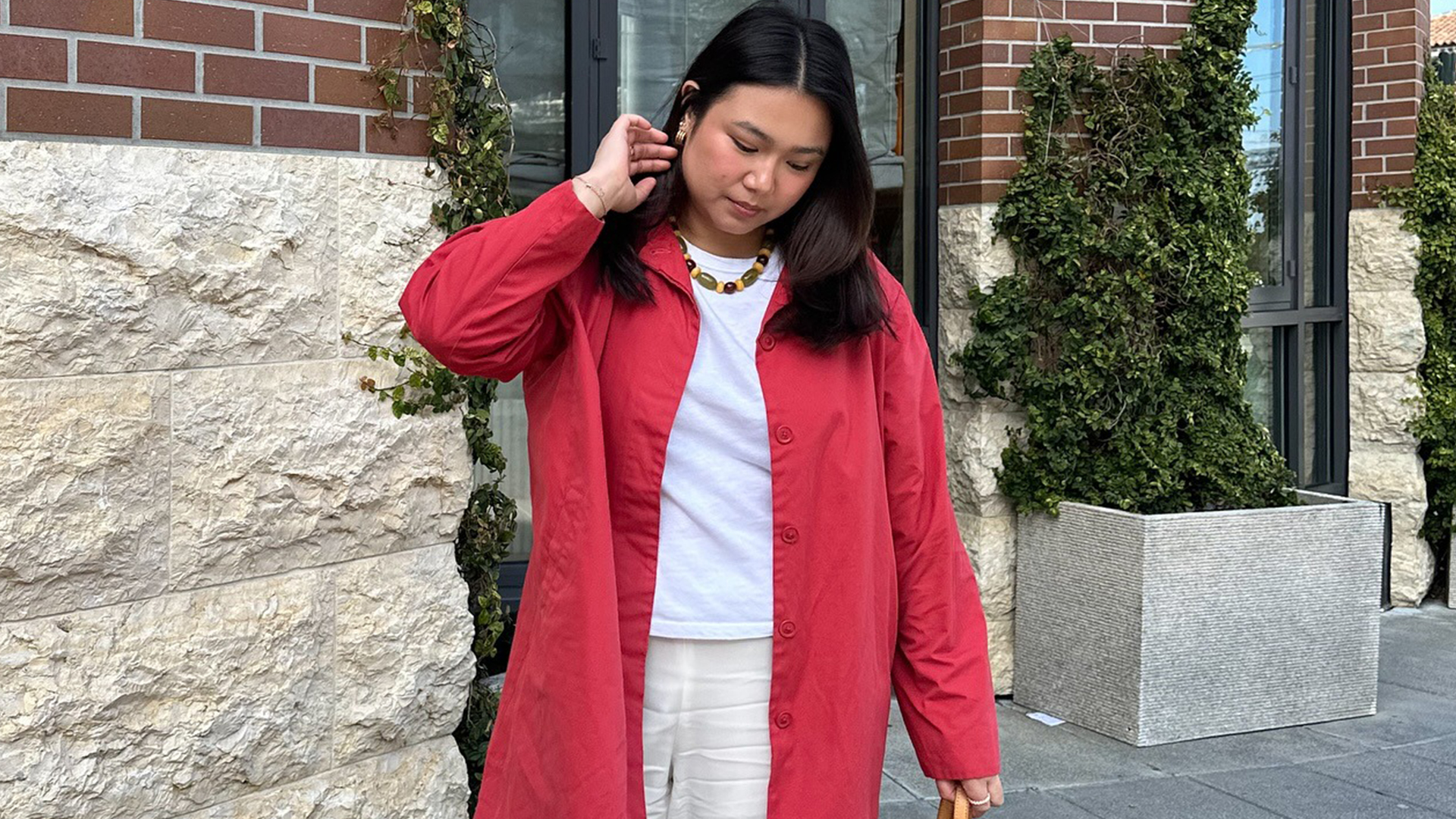 Marina wears whit linen pants, white t-shirt, and red shirt dress. Marina is also wearing a beaded necklace. 