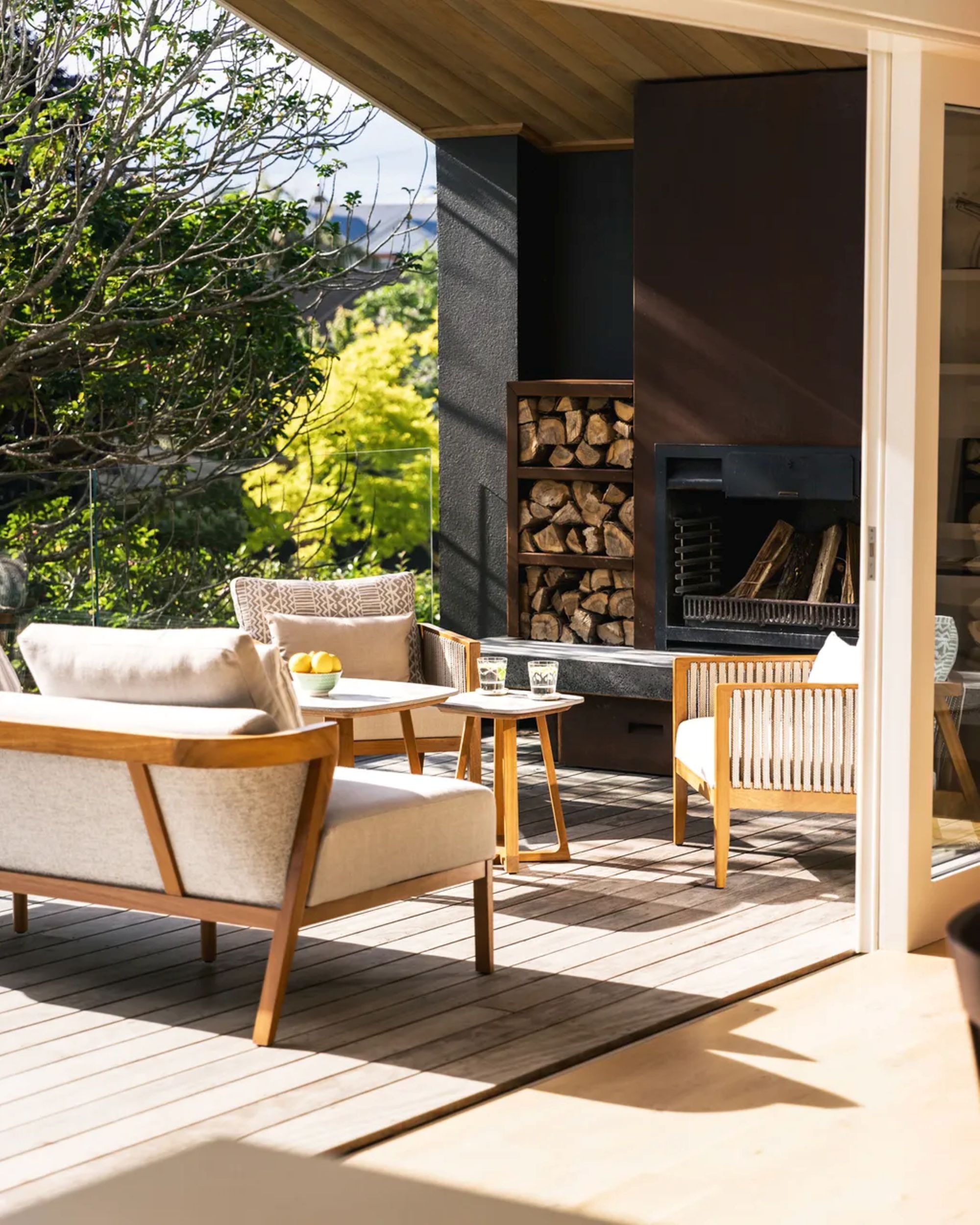 outdoor patio space with a couch, two chairs, and a fireplace built into the wall