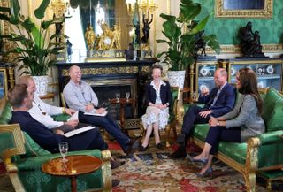 Alex Payne, James Haskell, Mike Tindall, Princess Anne, Prince William and Princess Kate sitting on green chairs in a room at Windsor Castle and laughing