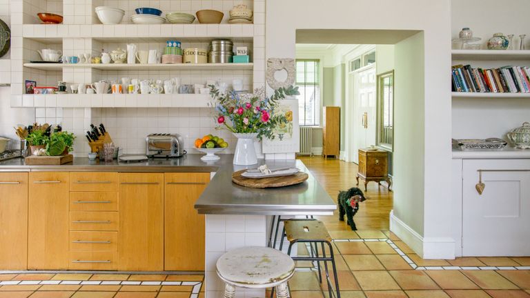 kitchen counter with salvaged stools and open shelves in Victorian home and view to hall