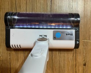 Clean indicator light sensor on Shark Cordless Detect Pro Auto Empty Vacuum Cleaner brush head, as illustrated on hardwood flooring