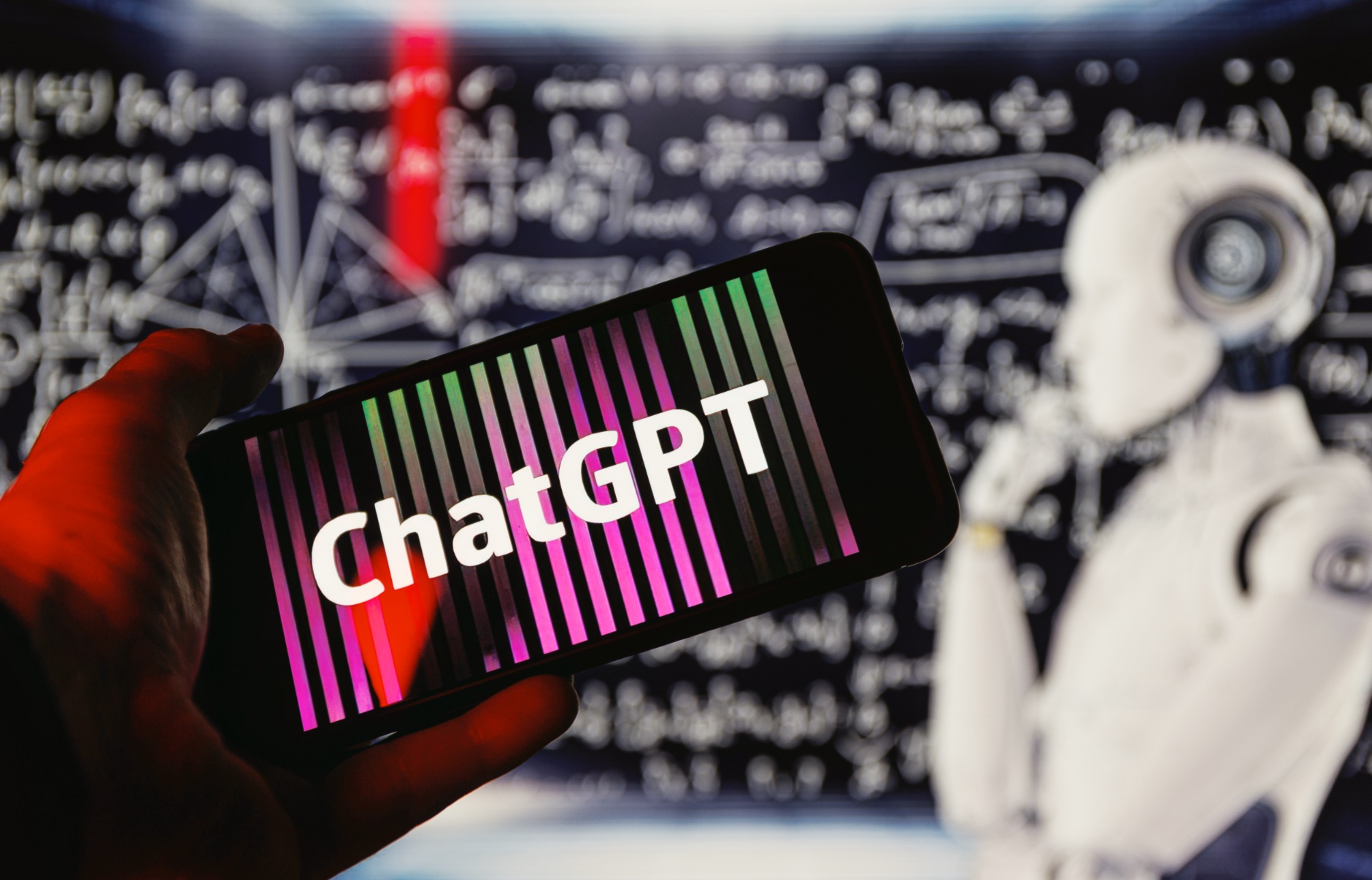 ChatGPT logo on phone in front of robot thinking
