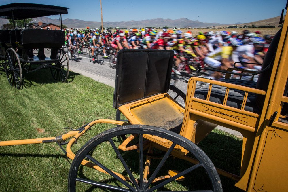 The peloton passes by old carriages along the route.