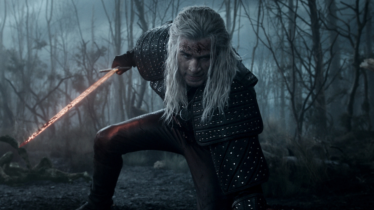 Geralt (Liam Hemsworth) wielding a glowing red sword in a scene from 
