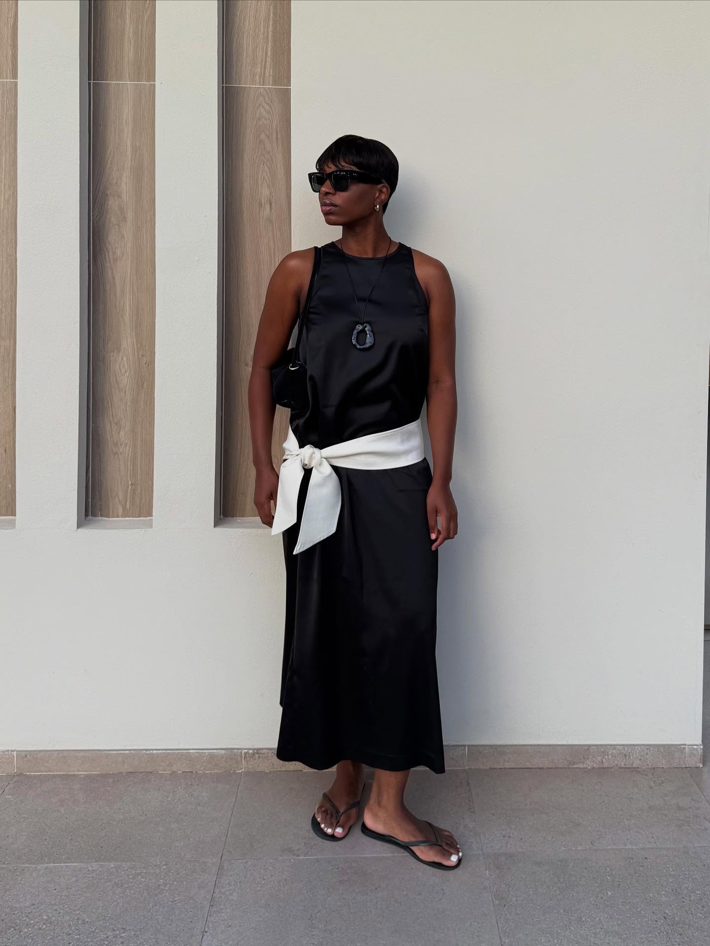 A woman on holiday in a black silky dress with a sleek pixie hairstyle