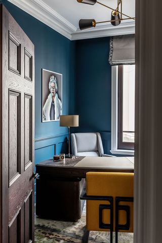 study with dark wood desk and yellow chair with blue walls