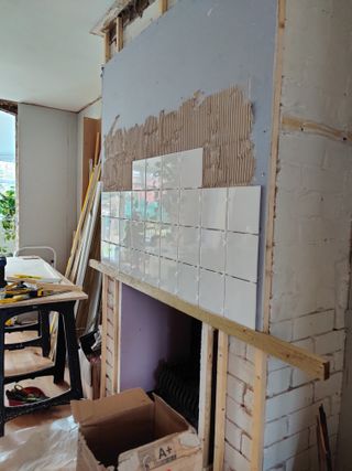 tile being added to a brick fireplace with a structure to hold the tiles