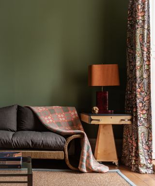 A living room with dark green walls and wooden side table