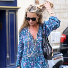 Kate Moss walks down the street in Paris wearing a paisley throw-on dress with heeled lace-up ankle boots.