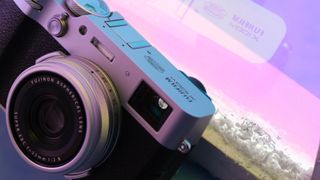 Fujifilm X100VI camera in front of a purple neon light