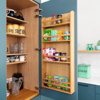 blue kitchen cabinet with food and mugs stored inside