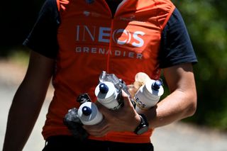 An Ineos Grenadiers soigneur waits to hand out drinks, gels, and food to the riders at the Tour Down Under