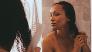 Woman in Bathroom Combing Hair - stock photo