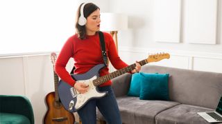 Woman playing electric guitar with headphones on