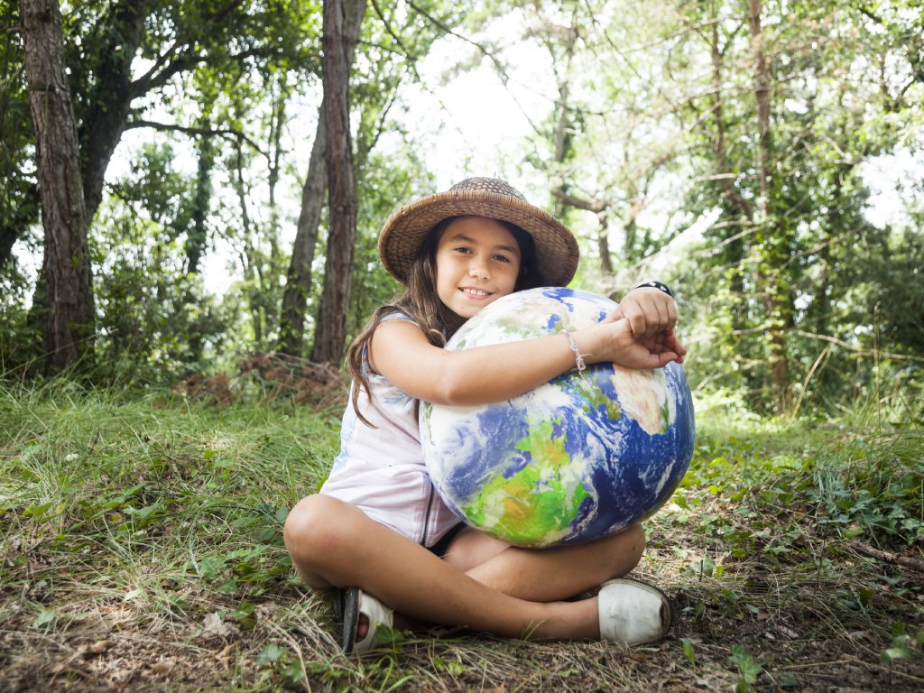 Smiling girl holding a globe in the forest