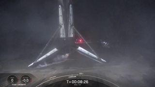 A black and white spacex falcon 9 rocket first stage sits on the deck of a ship at sea.