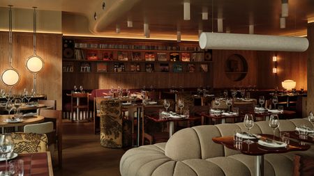 A restaurant with records-filled wooden walls, with spherical sconces, paper lanterns, wood and chrome tables, and eccentric plush fabrics.