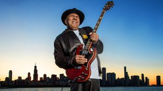 A photo of Ronnie Baker Brooks playing his 1967 Gibson SG with the Chicago skyline behind him