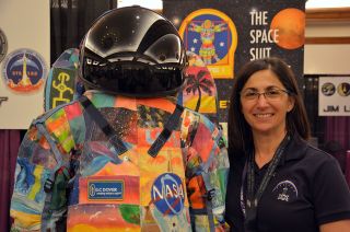 Astronaut Nicole Stott poses with a suit created by The Space Suit Art Project, a campaign to raise awareness of childhood cancer by MD Anderson Cancer Center, NASA and ILC Dover.