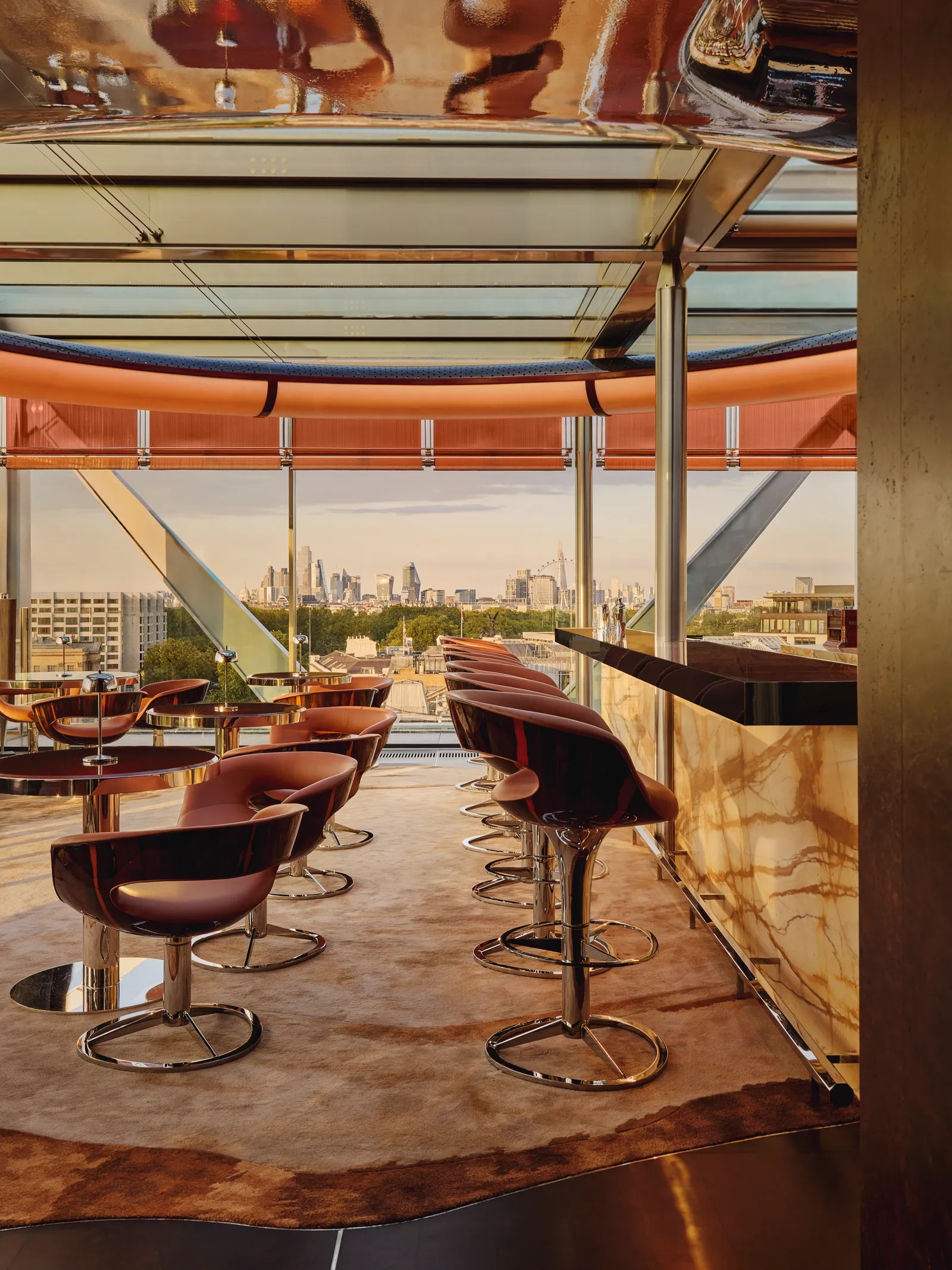 A sun-filled, swanky rooftop bar with reflective surfaces, Space Age-inspired leather seats and stools, and a leather carpet.