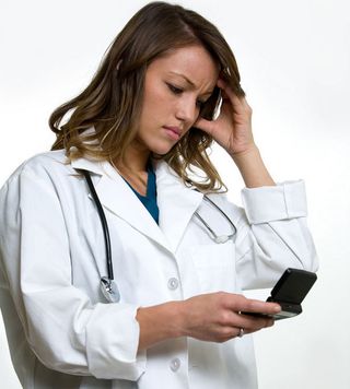 A young doctor looks at her cell phone, dismayed at what she sees.