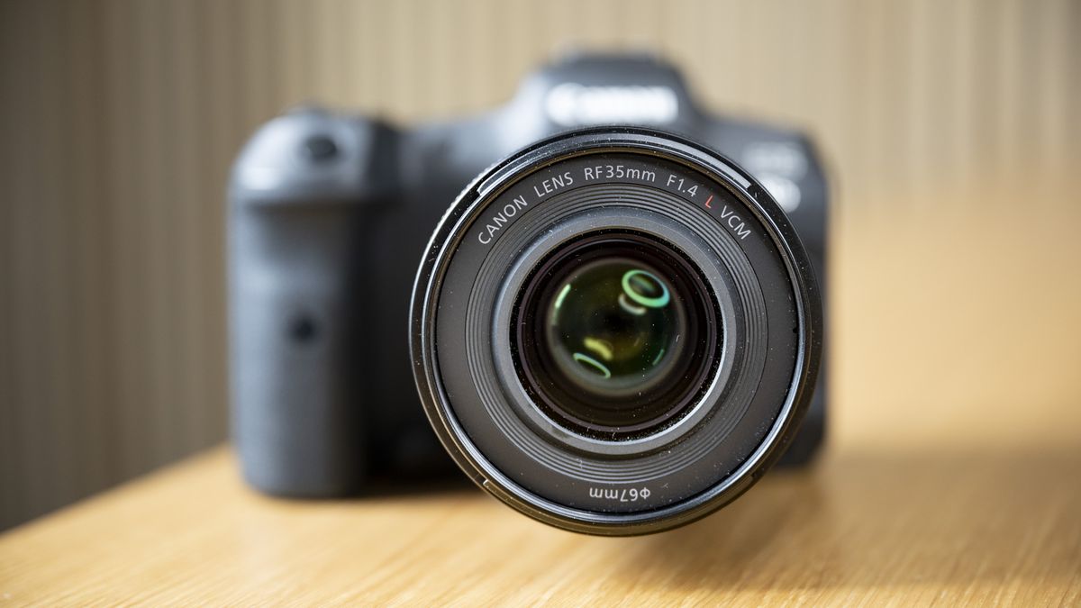 The Canon RF 35mm F1.4 lens on a wooden table, attached to a Canon EOS R5