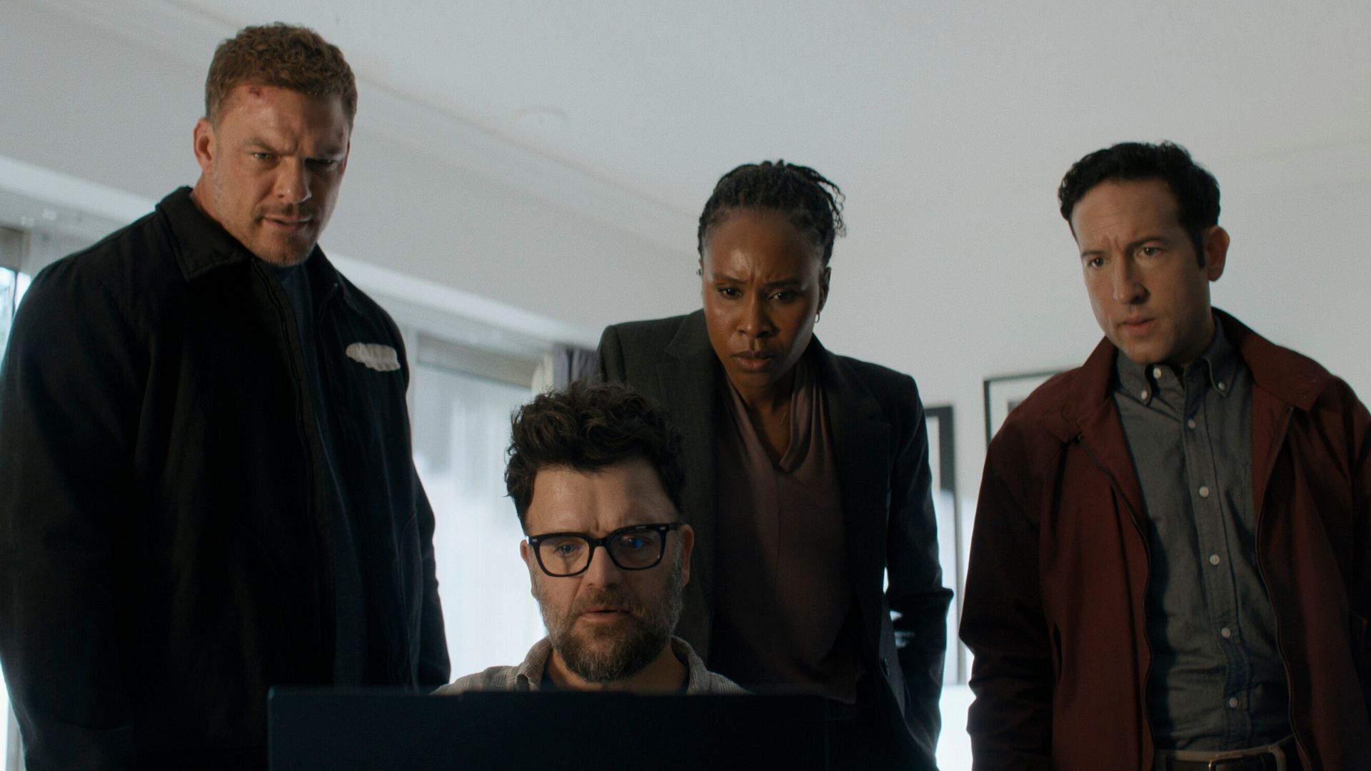 Three men and a woman stare at a computer screen