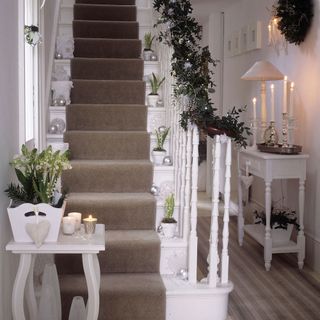 White staircase with potted plant onto each step surrounded by baubles with decorated balustrade