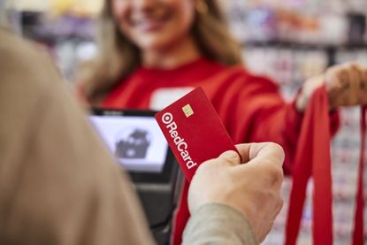 Man at Target store checkout presenting branded RedCard credit card for payment.