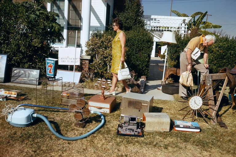 A couple in a garden walking around random household items