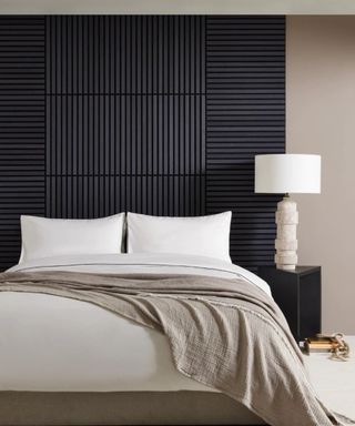 black panelled wall section behind bed with white and beige bedding