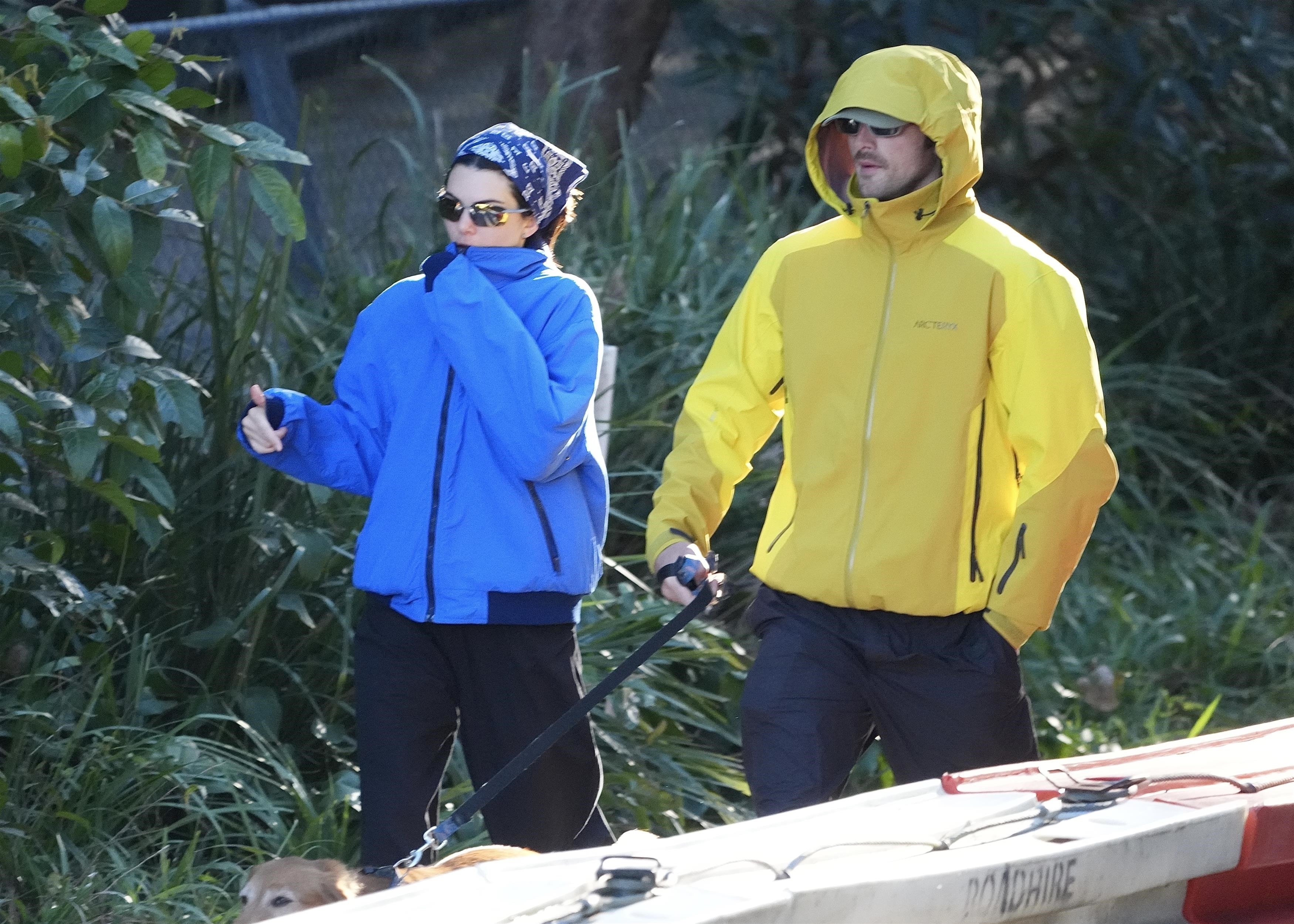 Kendall Jenner and Jacob Elordi walk a dog outside wearing technical jackets in blue and yellow. Kendall wears a bandana on her head and the two shield their eyes with sunglasses.