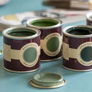 Farrow & Ball paint sample pots on a blue table, open tops