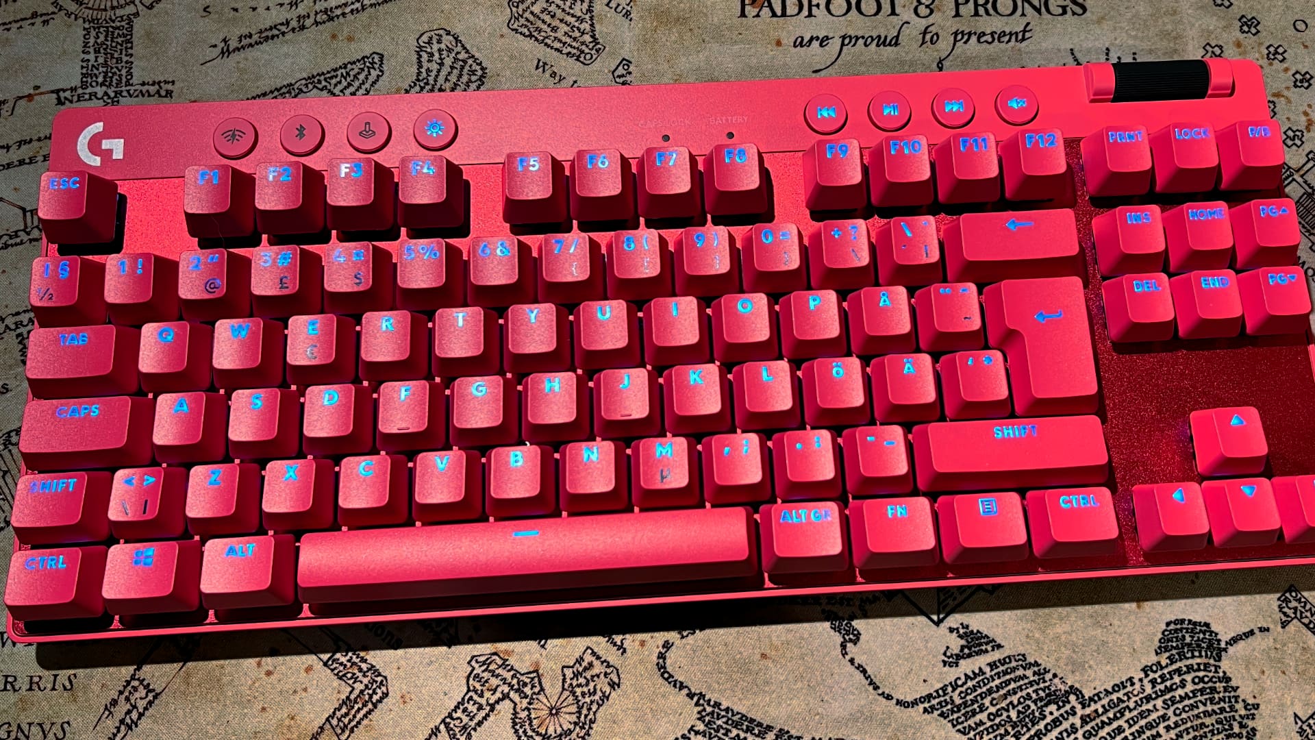 Ett chockrosa Logitech G Pro TKL ligger på en musmatta.