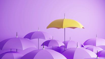 Yellow umbrella rising above a group of purple umbrellas against a purple background. 