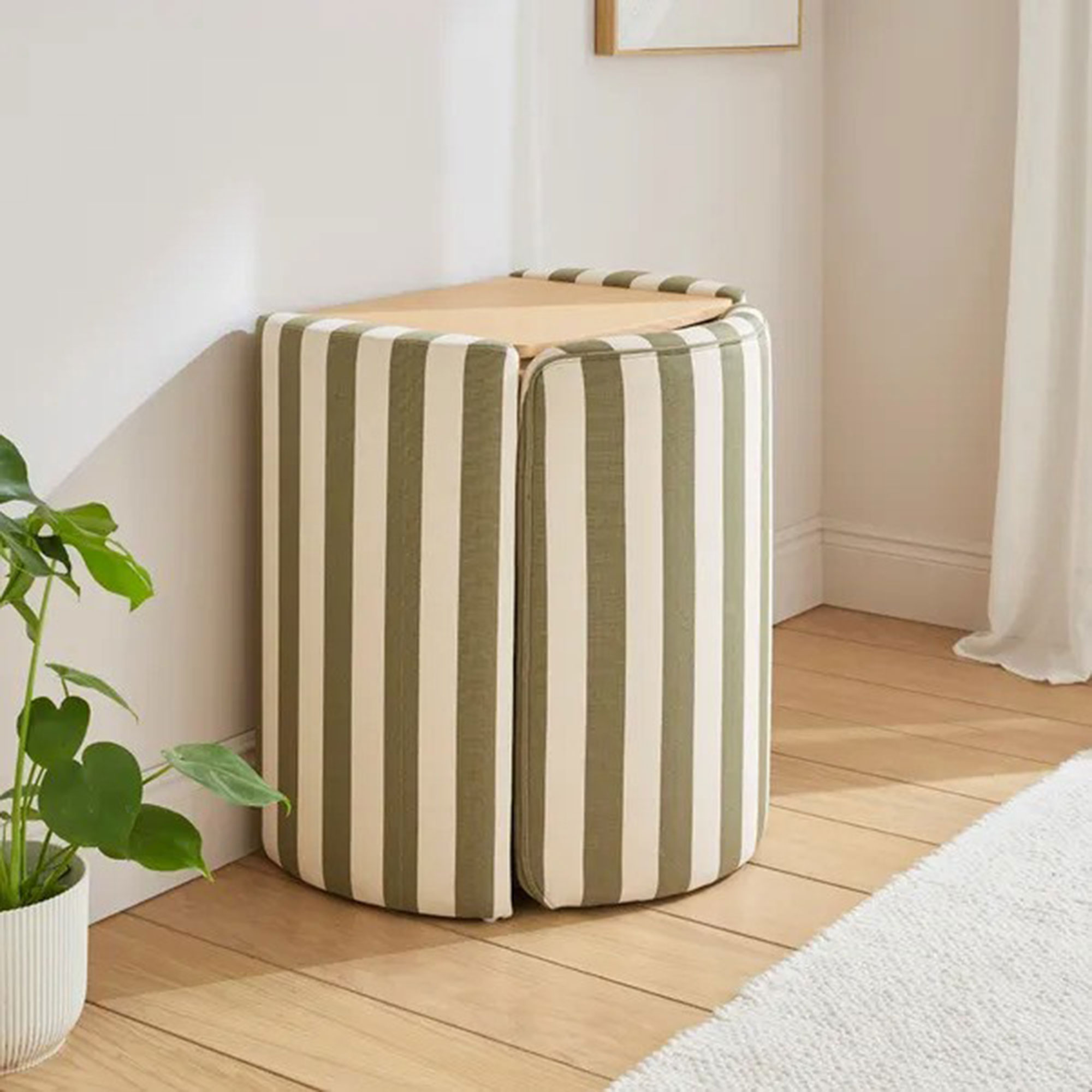 Dressing table in striped fabric in a white bedroom with the chair tucked in and the mirror down to show the wooden top
