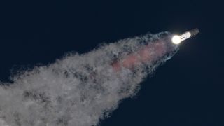 a massive rocket lifts off above a plume of fire at sunrise