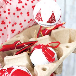 Red and white Christmas baubles in egg box