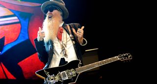 Billy Gibbons gives it the thumbs up onstage – he has his black custom Gretsch, and wears shades and a wide-brimmed hat