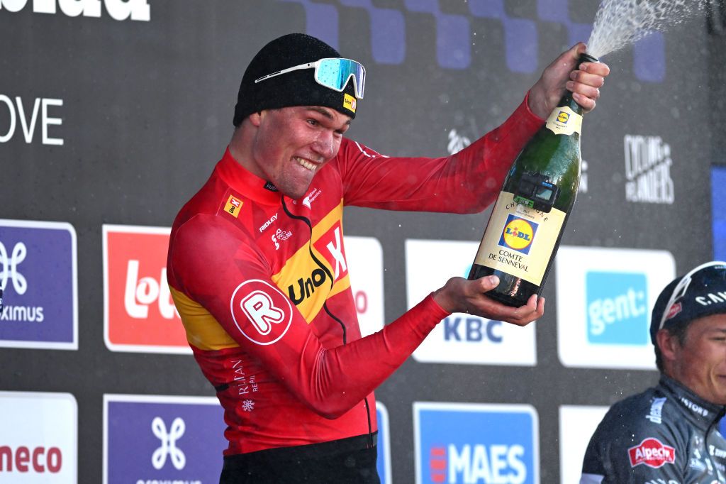 Soren Waerenskjold celebrates by spraying champagne on the podium of Omloop Het Nieuwsblad