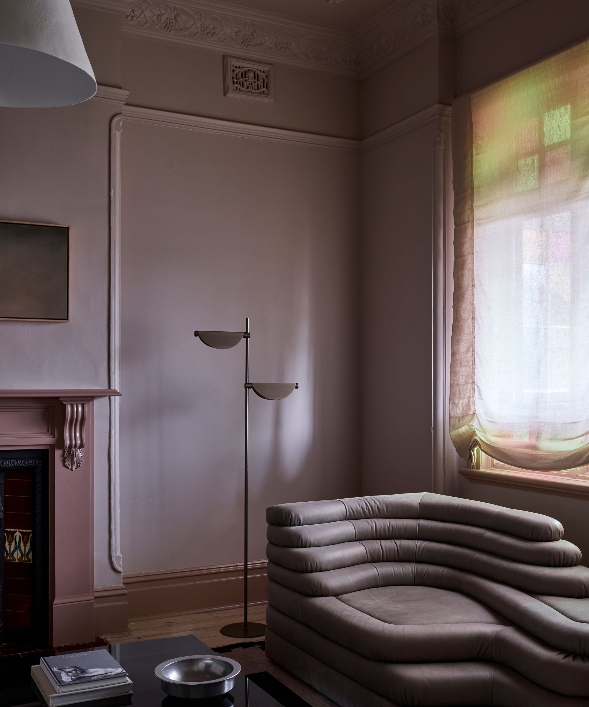 Living room with purple painted walls and fireplace, curved leather lilac sofa, midcentury metal floor lamp, a lacquer coffee table and a chrome ashtray
