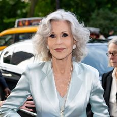a paparazzi photos of a white woman with shoulder length gray hair in baby blue silk blazer