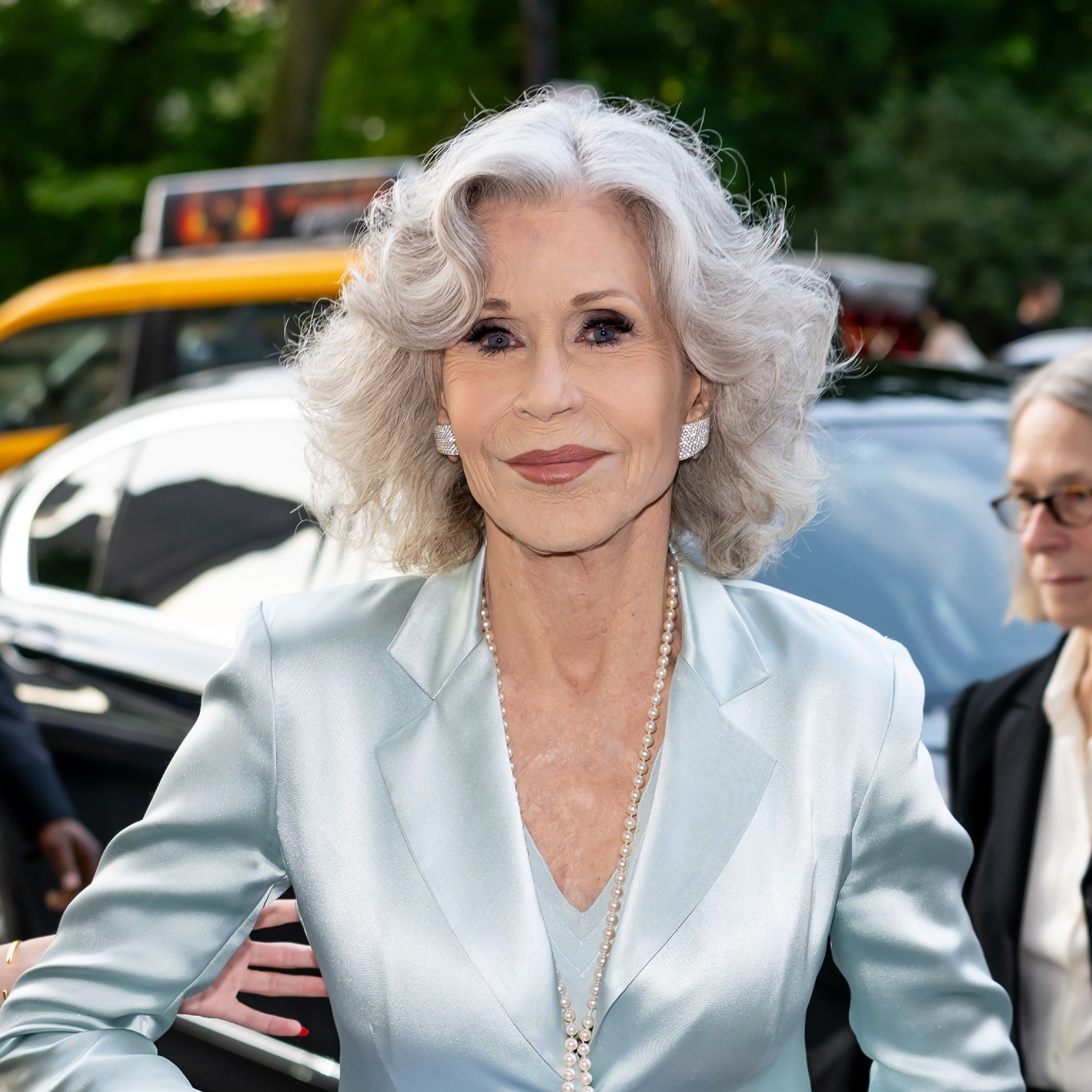 a paparazzi photos of a white woman with shoulder length gray hair in baby blue silk blazer