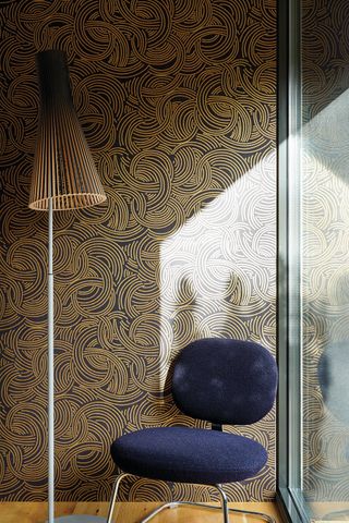 Busy wallpaper print in corner with velour low bar chair