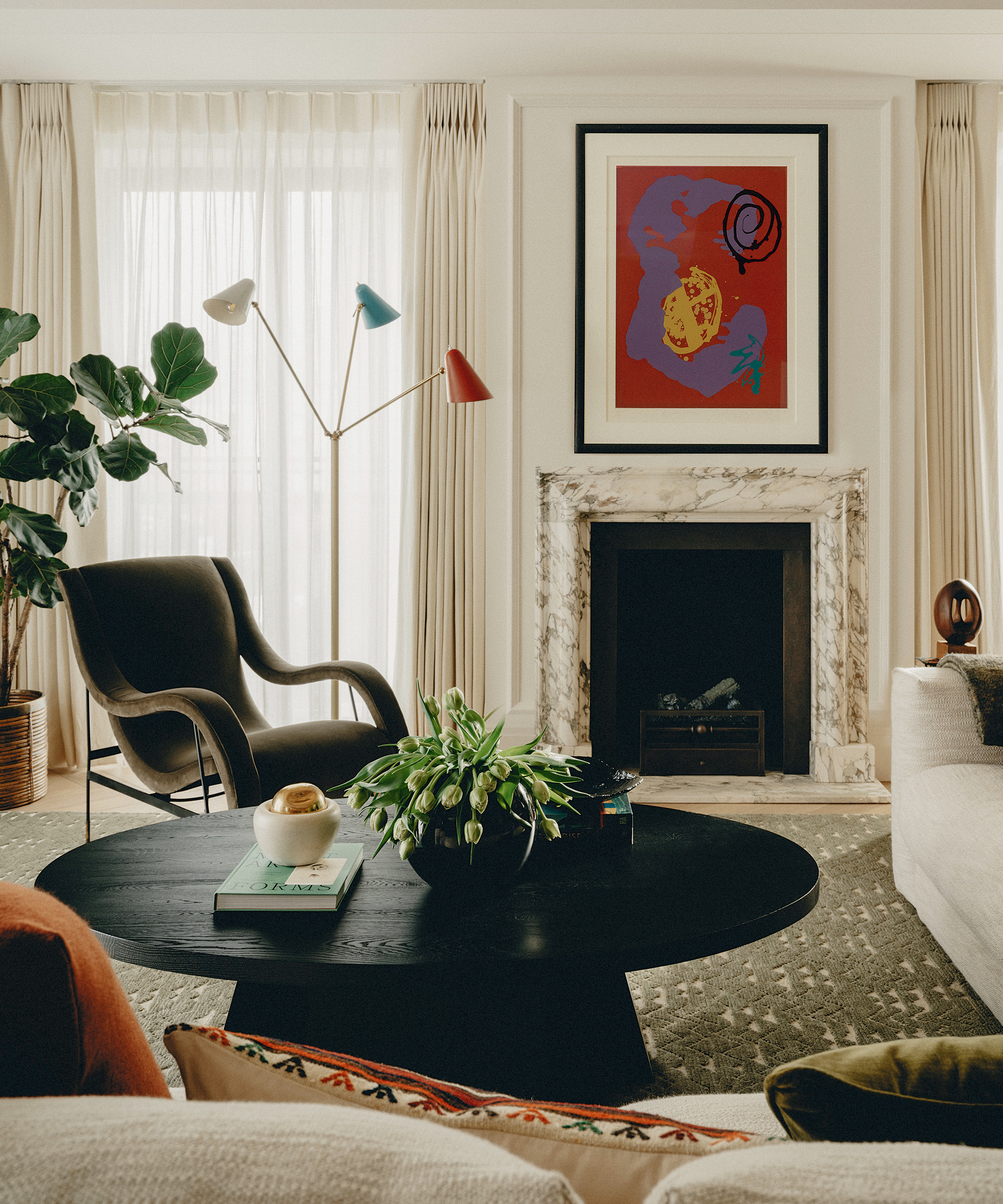 A living room with a patterned rug under a large round black coffee table