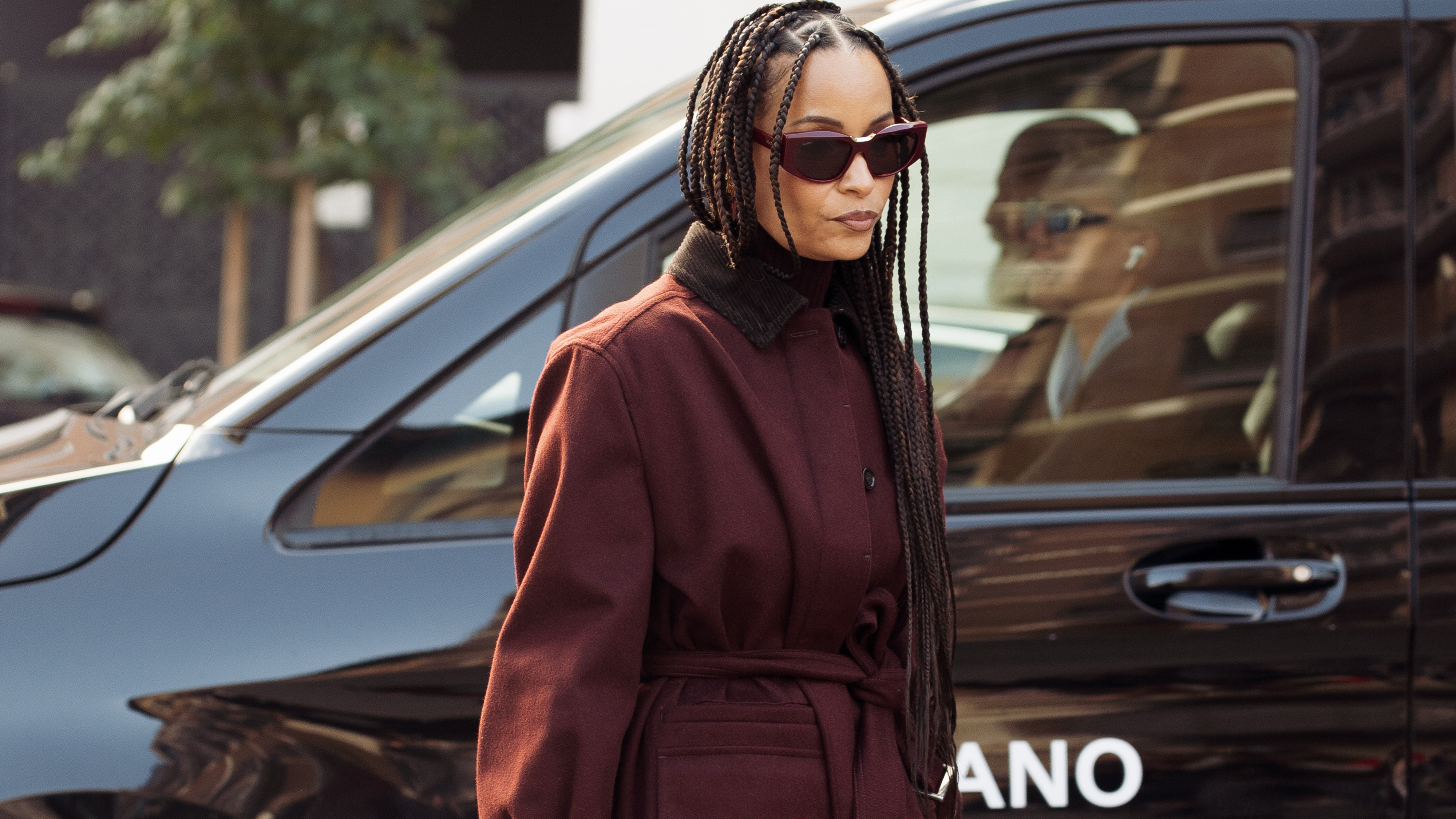 Sai De Silva wearing a burgundy coat.